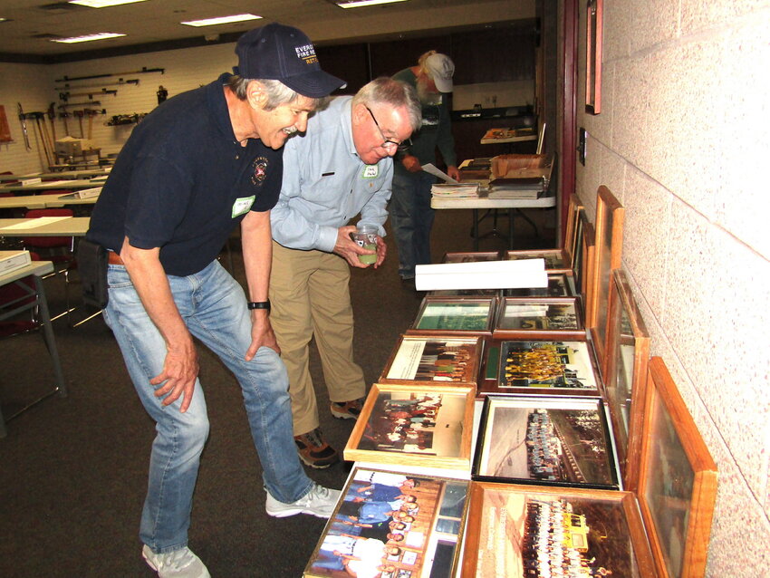 Mike Gregory, left, and Dick Merkel look at old photos of the fire department during the 75th anniversary celebration.